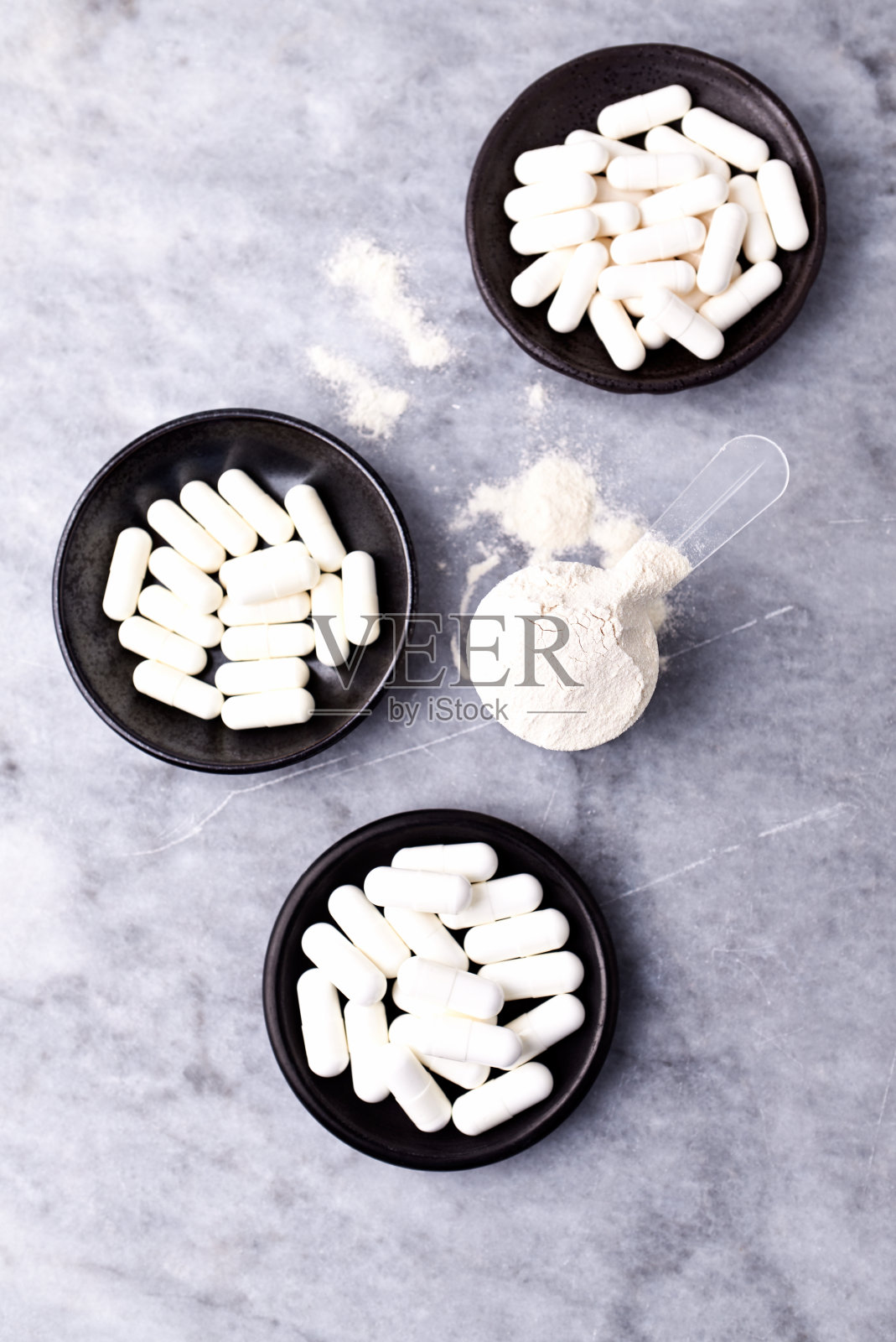 乳清蛋白,水解膠原I型,l -脯氨酸和l -賴氨酸膠囊勺。補充膠原蛋白的生產。明亮的石頭背景。直接上圖。副本的空間。